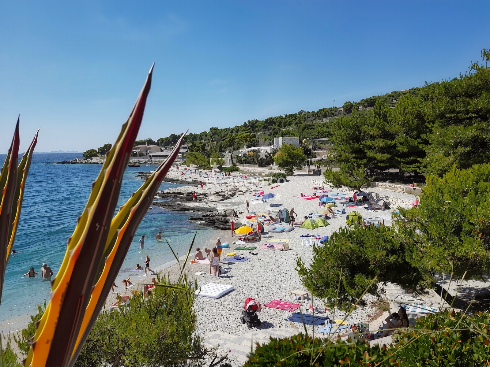 Tepli Bok Beach, Central Dalmatia, Croatia with rocky shoreline and boats in the distance