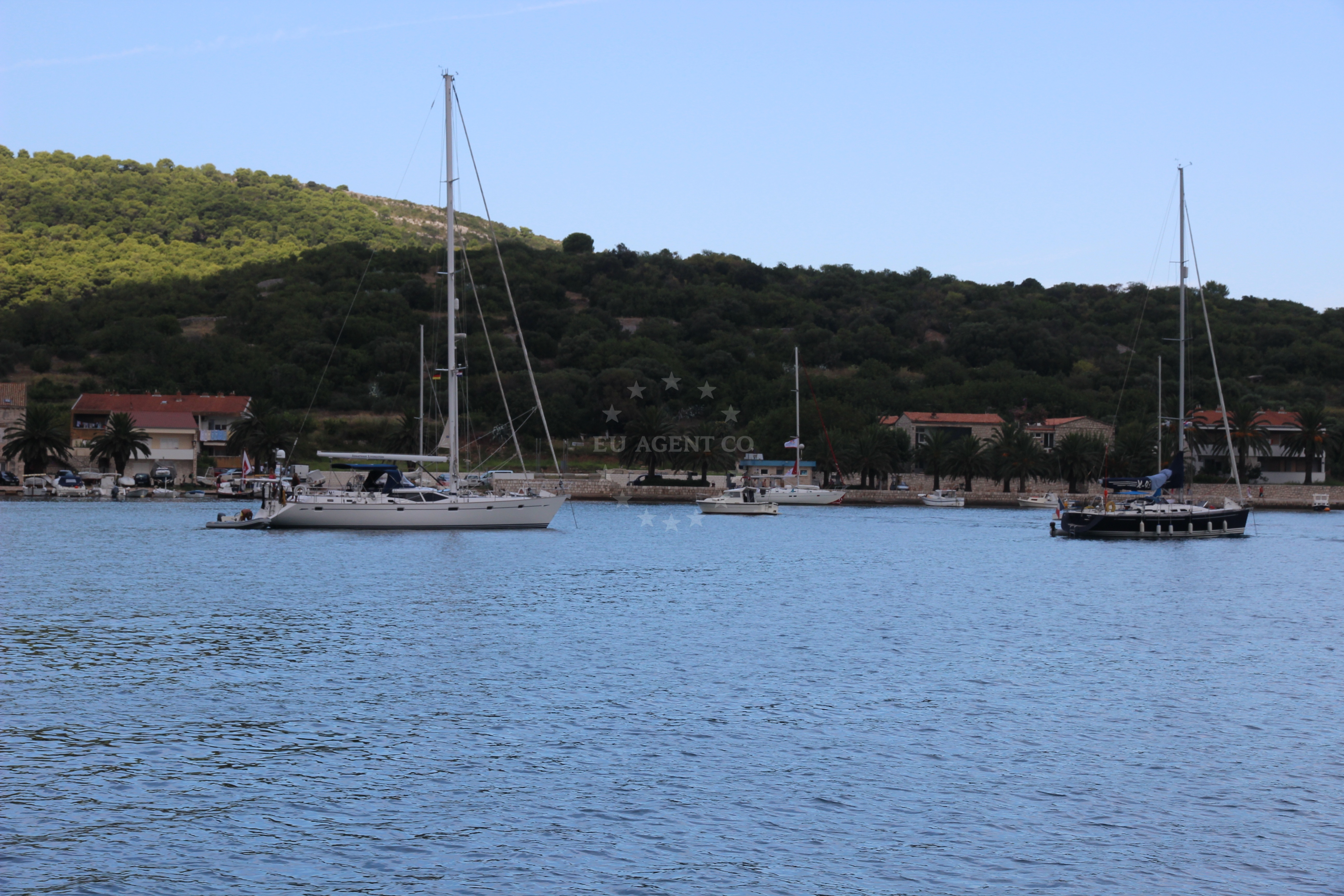 Sailboats anchored at Vis Luka with nearby harbor in the distance
