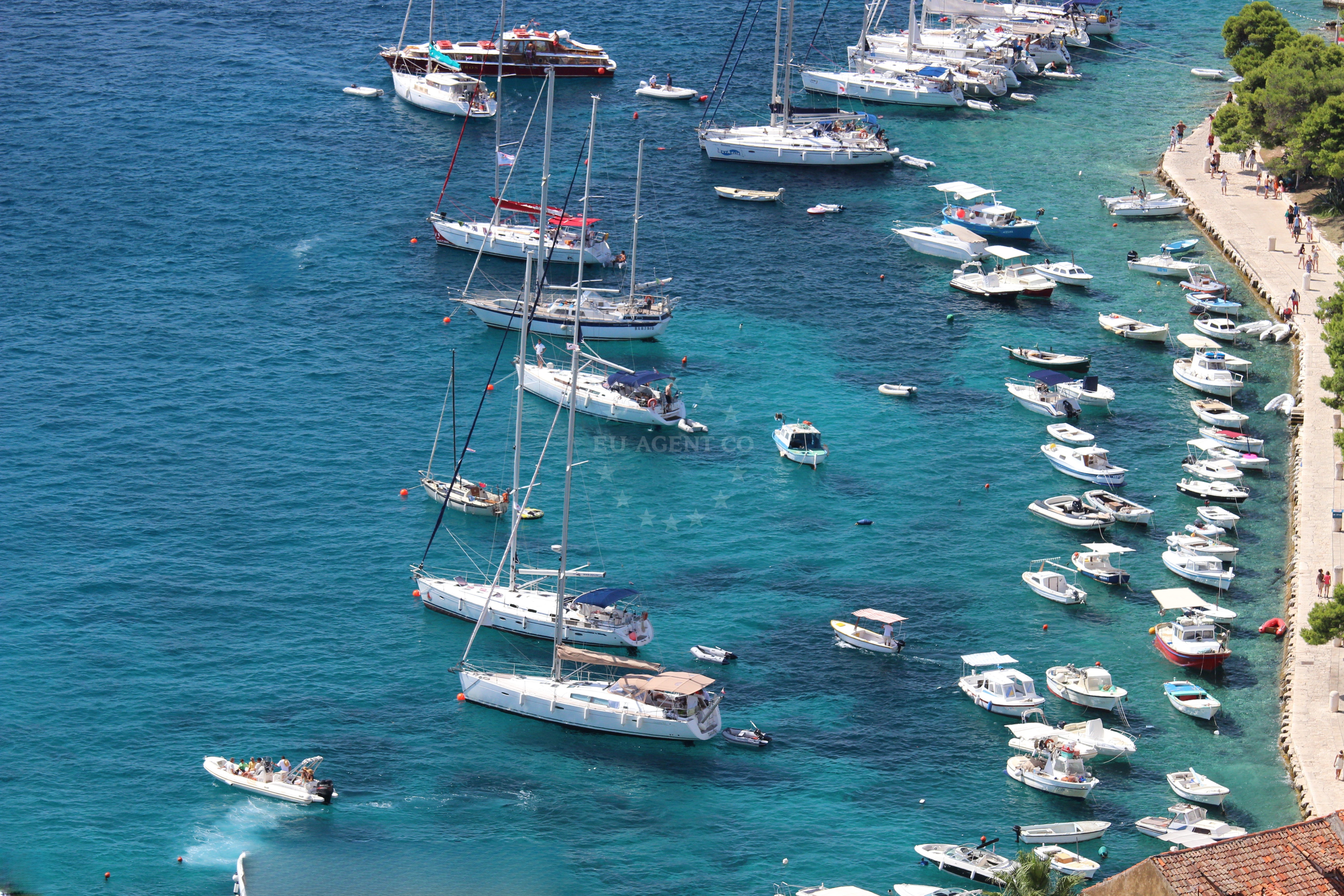 Sailor anchoring at Hvar buoy field with nearby marina