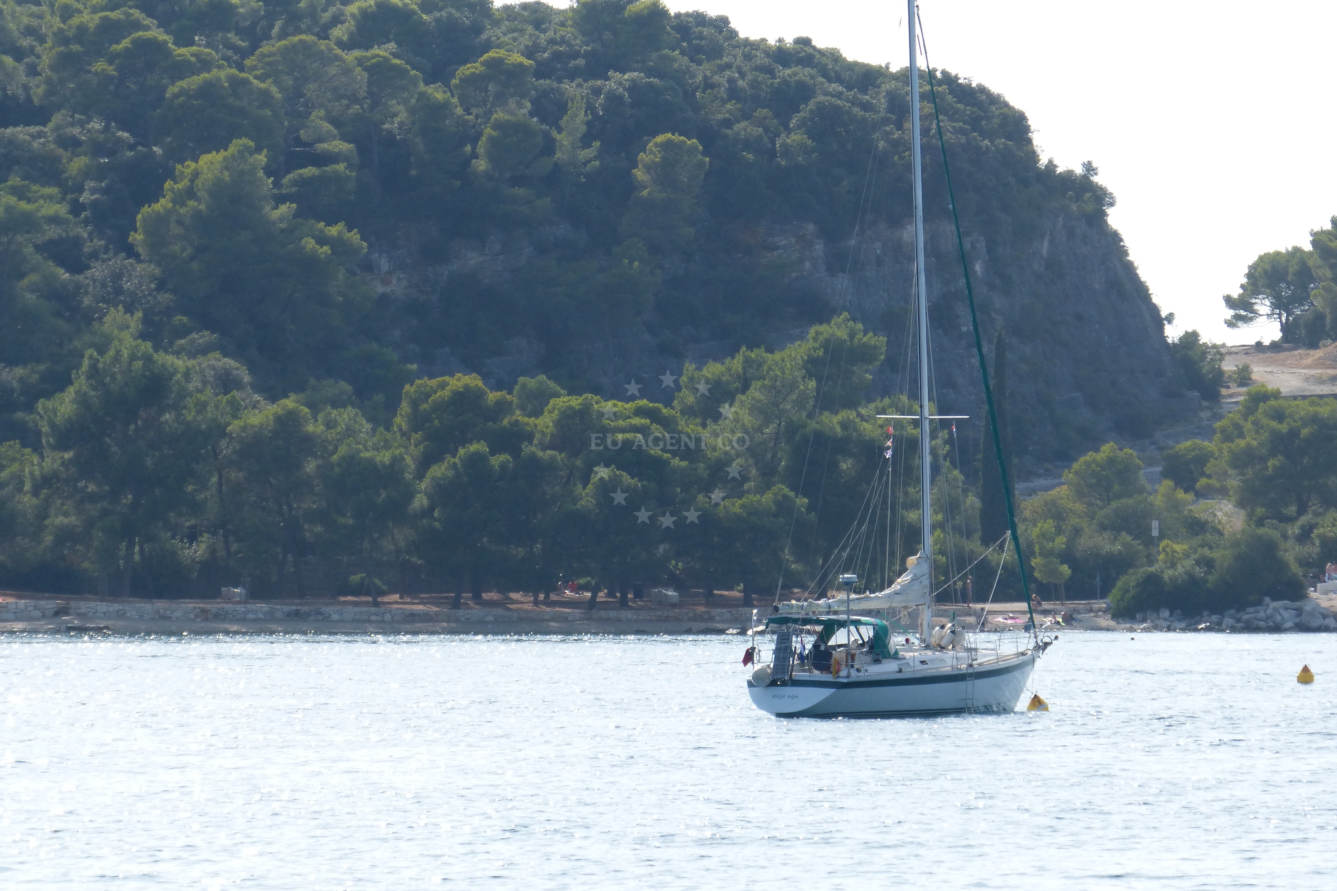Sailboat moored at Rovinj buoy field with nearby marina in view