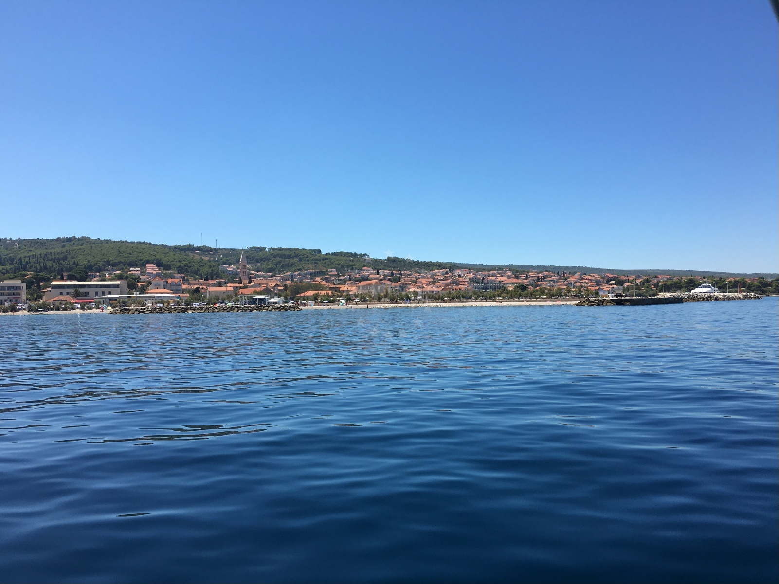 View of Supetar Harbour from the water with boats moored along the mole