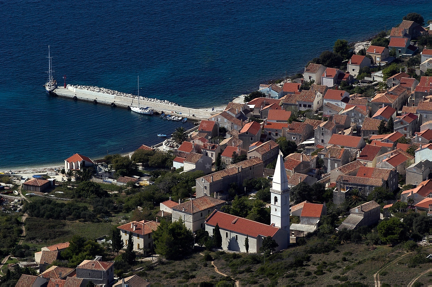 Unije Harbour with long breakwater and village houses in the background, Croatia