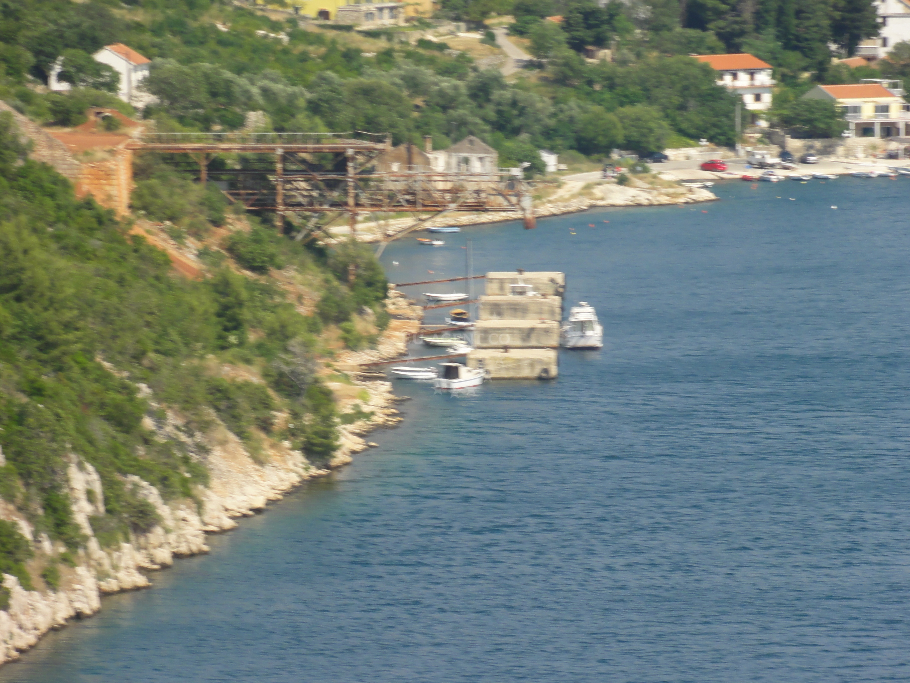 Maslenica Harbour, North Dalmatia, Croatia: A serene coastal harbor with nearby cliffs and boats anchored in the distance.