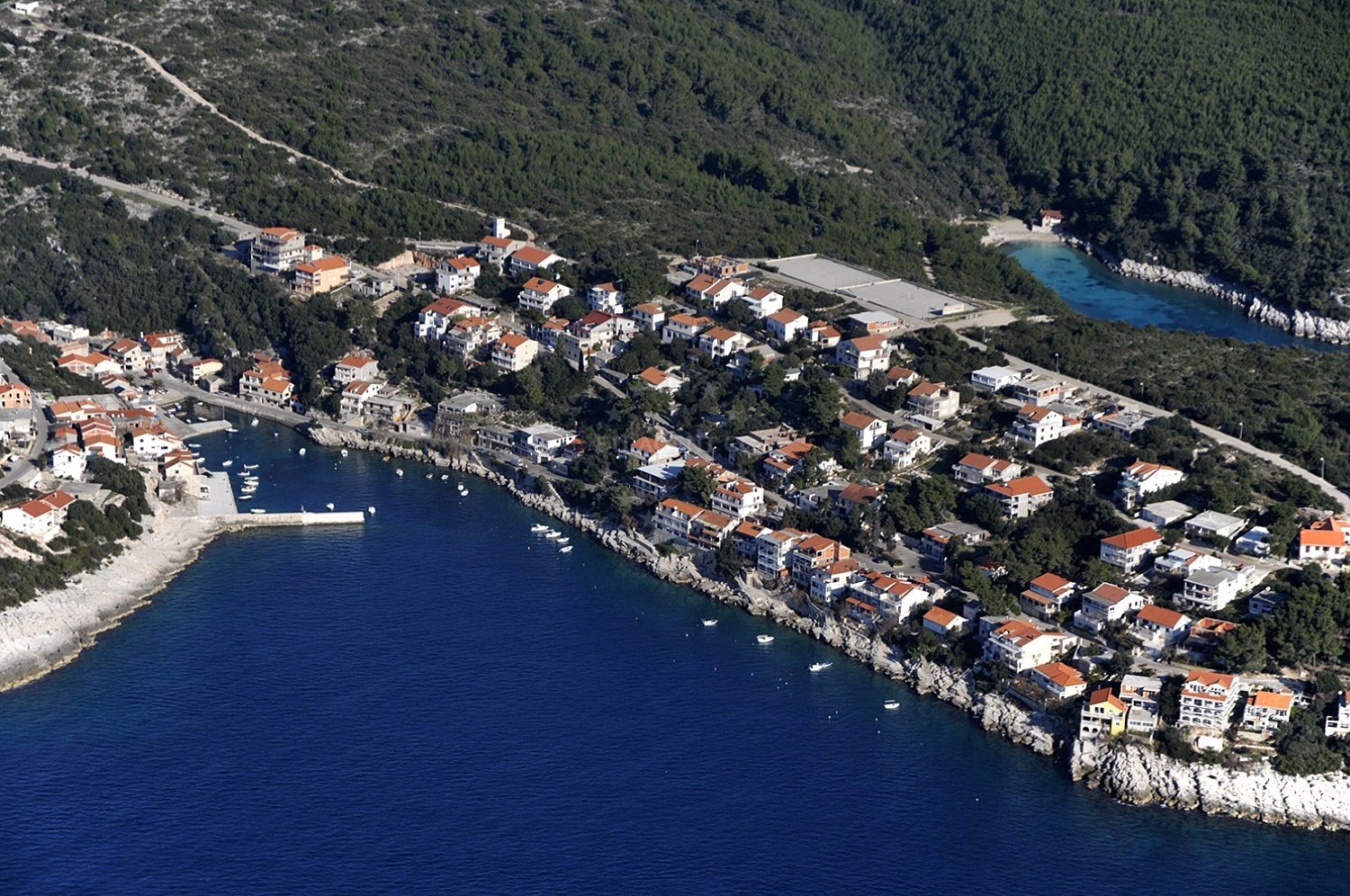 Zavalatica Harbour quay with moored vessels and nearby restaurant