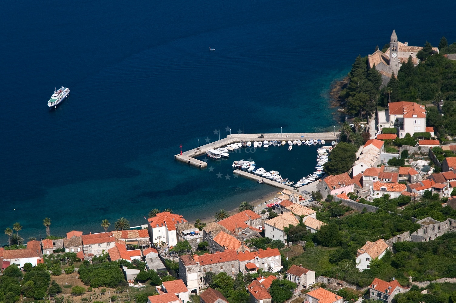 Lopud Harbour entrance with local vessels and nearby pebble beach