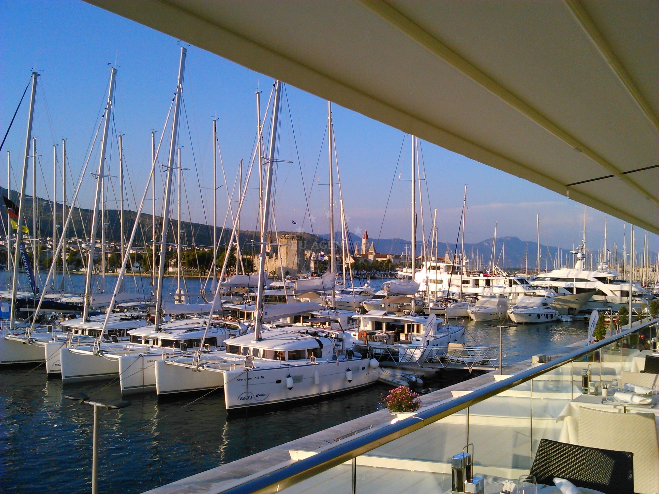 Marina Trogir jetty with yachts docked and historical Trogir in the distance